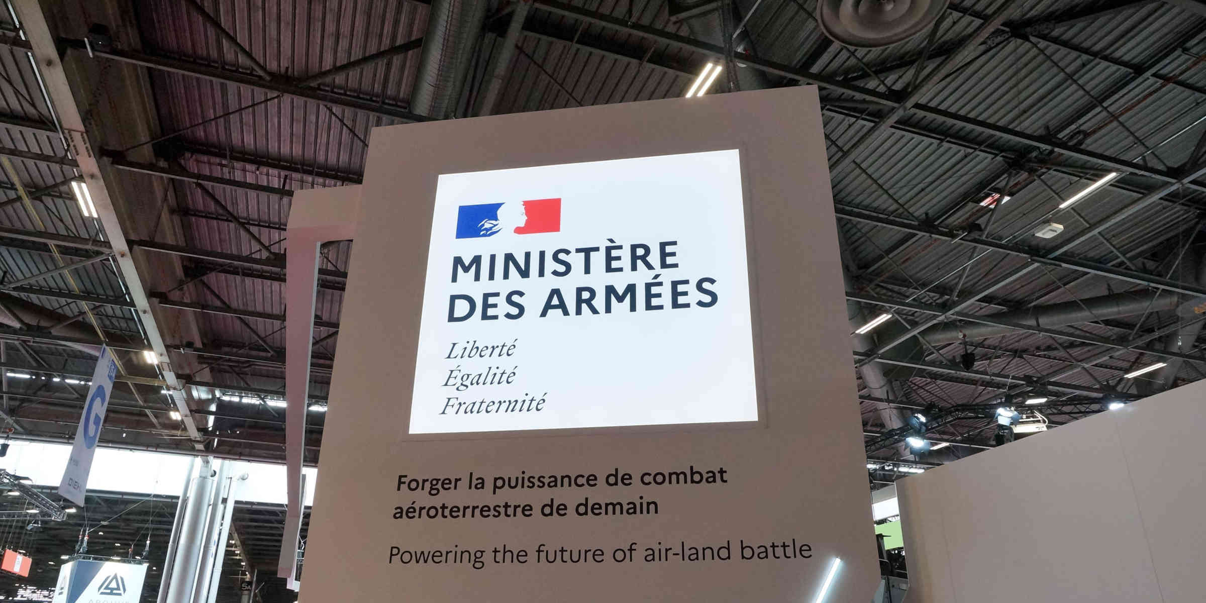 Exhibition booth sign for the French Ministry of the Armed Forces with the motto Liberté Égalité Fraternité and a bilingual mission statement.